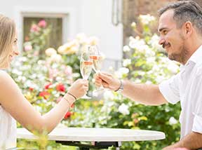 Zwei Personen stoßen mit Prosecco an – romantischer Moment im Garten des Hotel Gollner Graz.